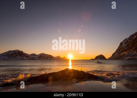 La famosa spiaggia di sabbia nei pressi di Haukland durante il tramonto sul Lofoten isole in Norvegia in chiaro giorno d'inverno con neve-rivestito montagne e cielo blu Foto Stock