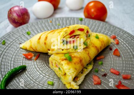 Semi-tagliati di Omelet DOSA in un piatto con pomodoro, uova e cipolle Foto Stock