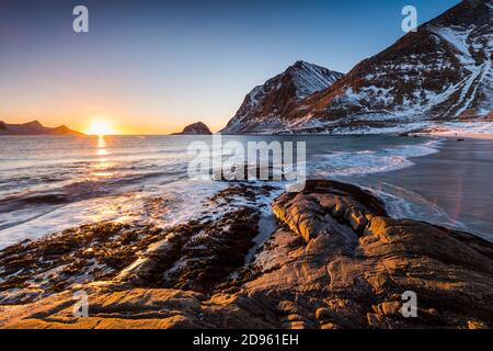 La famosa spiaggia di sabbia nei pressi di Haukland durante il tramonto sul Lofoten isole in Norvegia in chiaro giorno d'inverno con neve-rivestito montagne e cielo blu Foto Stock