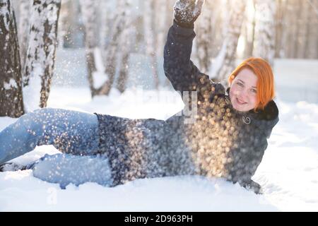Ragazza vuole giocare palle di neve mentre si trova nella neve nella foresta invernale. Donna circondata da fiocchi di neve. Foto Stock