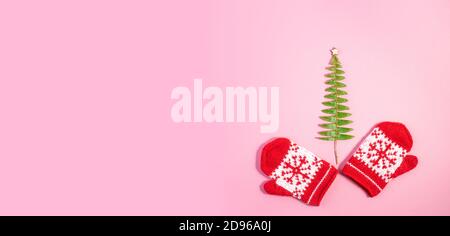 Christmas Red Mittens lavorato a maglia con motivi Snowflake su sfondo rosa pastello alla moda. Natale nuovo anno concetto minimo con spazio di copia. Lungo largo b Foto Stock