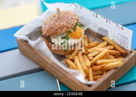 Primo piano di hamburger di manzo su sfondo tavola di legno. Hamburger di carne alla griglia hamburger, lattuga, pomodoro e uova fritte. Hamburger gourmet fatto a mano Foto Stock