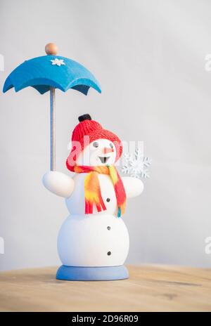 Pupazzo di neve decorativo con umberella con cappello rosso e sciarpa. Foto Stock