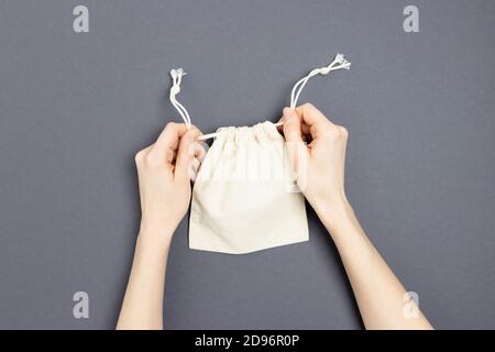 Le mani femminili stringano i lacci su una piccola borsa di tela. Foto Stock