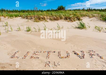 Lietuva parola scritta con pietre sulla riva, spiaggia sabbiosa sul Mar Baltico in Lituania Foto Stock