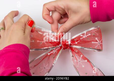 Donna che fa mestieri creando un arco rosso con motivi di Natale Foto Stock