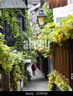 03 novembre 2020, Hessen, Rüdesheim: Una donna cammina da sola attraverso la famosa Rüdesheimer Drosselgasse. Un blocco parziale di quattro settimane è in vigore in tutta la Germania per rallentare la diffusione del coronavirus. Foto: Arne Dedert/dpa Foto Stock