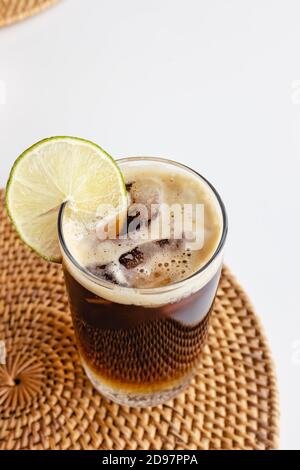 Espresso tonico in un bicchiere con cubetti di ghiaccio sul tavola bianca Foto Stock