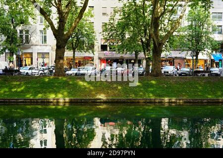 Il famoso viale dello shopping Königsallee: Vista sul verde canale della città 'Kö-Graben' dal lato 'tranquillo' al 'lato occupato' con molti negozi. Foto Stock