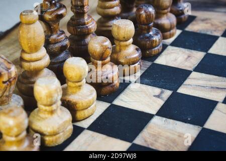 Pezzi di scacchi in legno d'oliva allineati su una scacchiera di legno scheda Foto Stock