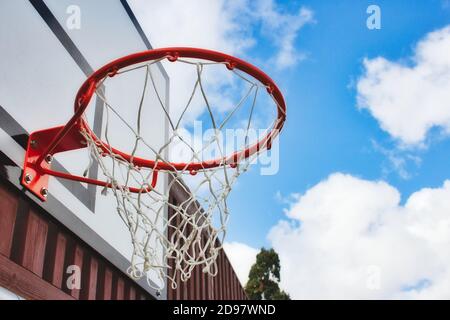 Cerchio da basket con rete da sotto con un cielo blu sfondo Foto Stock