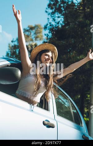 Ragazza teen che ondeggiava felicemente attraverso la finestra dell'auto Foto Stock