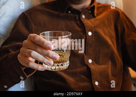Uomo seduto sulla sedia e bevendo whisky. Foto Stock
