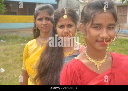 Primo piano di tre ragazze indiane adolescenti che indossano orecchini a collana con naso dorato sari maang tikka con make up, messa a fuoco selettiva Foto Stock