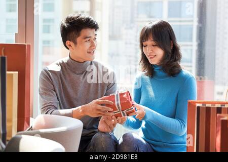 uomo asiatico che dà una ragazza giovane donna un natale o un compleanno regalo Foto Stock