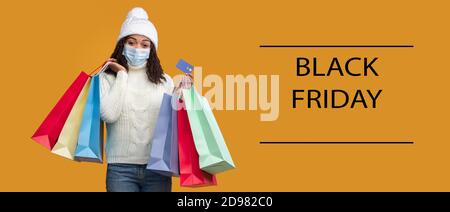 Black Friday. Donna afroamericana in maschera con carta di credito Foto Stock