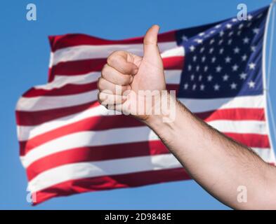 Concetto patriottico. Tumb up segno contro della bandiera degli Stati Uniti d'America Foto Stock