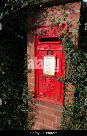 Scatola di posta britannica di colore rosso brillante montata a parete Foto Stock