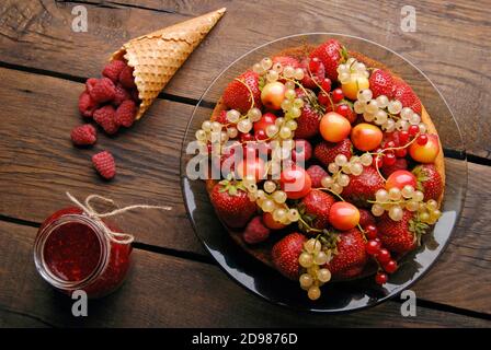 Pan di Spagna con diversi frutti estivi e lamponi in legno tabella Foto Stock