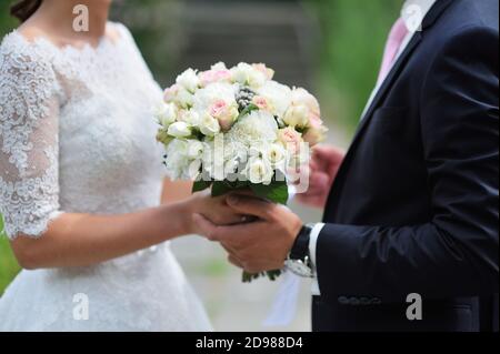 Lo sposo dà la sposa primo piano-in su bello bouquet di nozze. Per una passeggiata nel parco Foto Stock