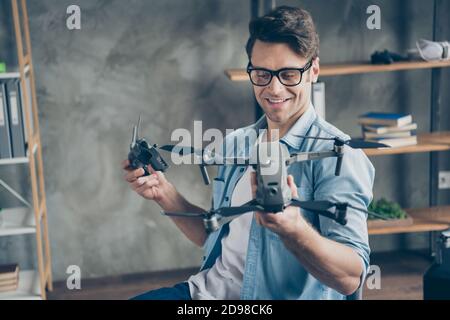 Ritratto del suo bel ragazzo allegro focalizzato attraente allegro geek professore che tiene in mani drone novità inventare sicurezza al loft moderno Foto Stock