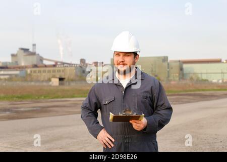 Ritratto di ingegnere in piedi sul cantiere e di tenere carte. Foto Stock