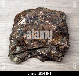 Grande pezzo di feldspar minerale sfaccettato lucido che giace su a. superficie in legno Foto Stock