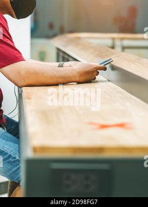 Uomo che usa telefoni cellulari per lavorare con immagine sfocata di il contrassegno di posto alternativo per la distanza sociale regola la distanza per uno posto da altre persone a p. Foto Stock