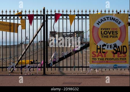 Nastri e una bandiera gialla defaced legata alle porte chiuse di Hastings Pier a East Sussex, Inghilterra, nel maggio 2011, sette mesi dopo un incendio devastante. Il molo vittoriano, inaugurato nel 1872, ha ospitato importanti eventi rock e pop negli anni '60, tra cui Pink Floyd, Jimi Hendrix, Rolling Stones e The Who. L'incendio distrusse il padiglione Hastings Pier da 2,000 posti nel 1972, il molo fu chiuso come una struttura pericolosa e il 5 ottobre 2010, una briciolo distrusse i restanti edifici in legno. I lavori di ricostruzione sono stati avviati nel 2011 e il molo riaperto nel 2016. Foto Stock