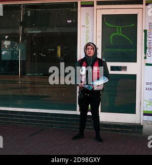 Senzatetto/ povertà/ vulnerabile / concetto di salario vivente - Ritratto di strada di un giovane uomo che tiene copie della grande edizione, Southend-on-Sea, Essex, Gran Bretagna Foto Stock