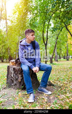 Sad e Pensive Young Man siedono nel Parco Autunno Da solo Foto Stock