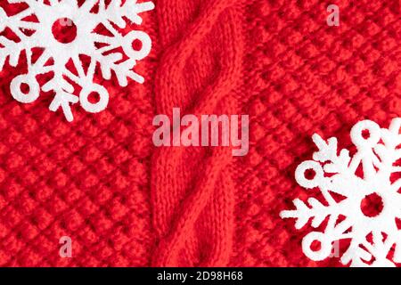 Caldo pullover natalizio rosso con fiocchi di neve come sfondo, primo piano. Layout, modello cartolina. Foto Stock