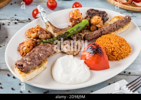 Griglia mista su tavolo di legno. Costolette di agnello, Adana kebab, shish di pollo, polpette di scoglio, bistecca. Foto Stock