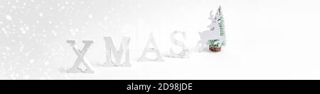 Natale festivo trendy minimo ampio banner bianco con decorazioni natalizie lettere XMAS, albero di Natale, cervo su bianco. Foto Stock