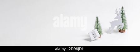 Natale festivo ampio banner bianco minimal. Decorazioni natalizie alberi di Natale, scatola regalo fai da te e cervi su bianco. Foto Stock