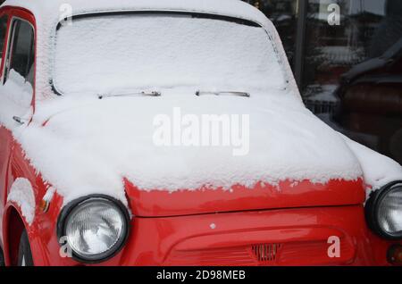 Auto rossa retrò sotto la neve in inverno. Festa invernale celebrazione e felice Capodanno concetto Natale, copia spazio. Auto d'epoca rossa coperta dopo un Foto Stock