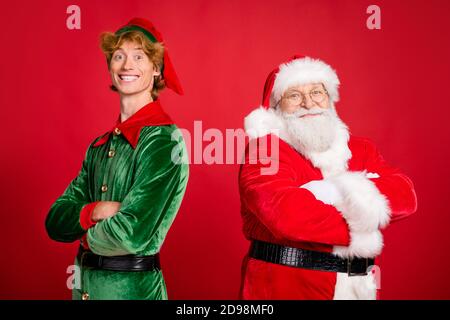 Foto di due uomini babbo natale elfo con le mani ripiegate indossare il costume x-mas cappotto copricapo isolato di colore rosso sfondo Foto Stock