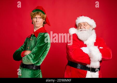 Foto di profilo di due persone babbo natale elfo braccia ripiegate argomento arrabbiato indossare x-mas costume cappotto isolato colore rosso sfondo Foto Stock