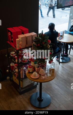 Decorazioni natalizie e souvenir in cima a un tavolo rotondo con albero di Natale. Silhouette di donna cinese irriconoscibile sullo sfondo. Shanghai, Foto Stock