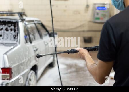 coronavirus pulizia della macchina, lavando la carrozzeria con un pulitore da soluzione di sapone. Il lavoro di tecnici automatici durante il periodo di quarantena COV Foto Stock