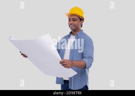 Il piano della casa di tenuta del lavoratore di costruzione in mani che la guardano. Architect Holding Blueprint. Elmetto rigido giallo. Foto Stock