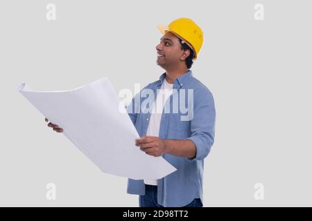 Il piano della casa di tenuta del lavoratore di costruzione nelle mani che guardano in su. Architect Holding Blueprint. Elmetto rigido giallo. Foto Stock