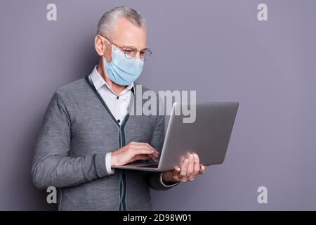 Ritratto del banchiere messo a fuoco che indossa maschera casual formale-wear utilizzando netbook e-commerce isolato su sfondo grigio pastello Foto Stock