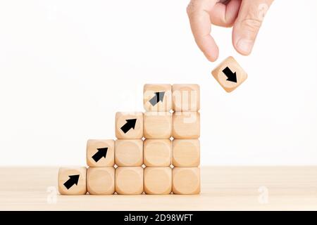 Mano e blocco di legno con freccia in discesa. Il crollo del mercato azionario o il concetto di crisi dell'economia finanziaria. Concetto di incertezza aziendale e idea di rischio. Copia Foto Stock