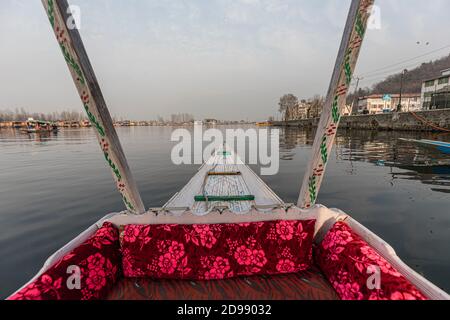 Una vista dall'interno di uno shikara con vista offuscata dell'acqua circostante e l'edificio intorno al lago dal. Foto Stock