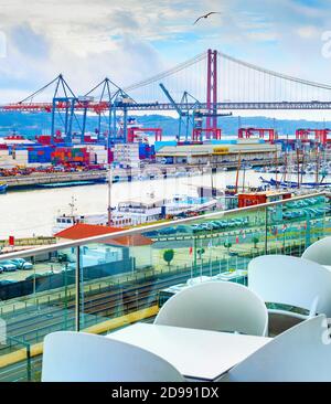 Vista porto commerciale di Lisbona dalla terrazza ristorante all'aperto, container, gru merci, motoscafi, binari ferroviari e parcheggio auto, ponte 25 aprile Foto Stock