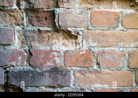 Primo piano muro di mattoni rosso danneggiato, sfondo selettivo, spazio di copia Foto Stock