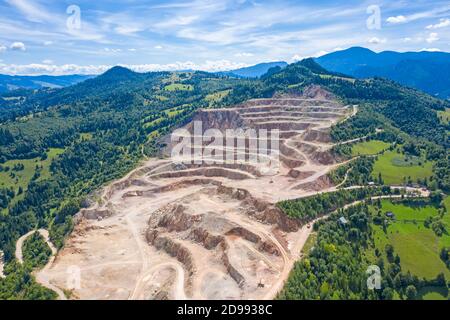 Vista aerea della cava di cemento, delle terrazze rocciose e dei dumper in funzione Foto Stock