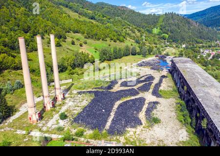 Vista aerea della discarica di pneumatici, pali di pneumatici di rifiuti vicino a edifici abbandonati Foto Stock
