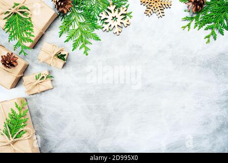 Composizione di Natale. Regali di Natale, coni di pino, rami di thuja e fiocchi di neve di legno. Vista dall'alto, disposizione piatta. Spazio di copia Foto Stock